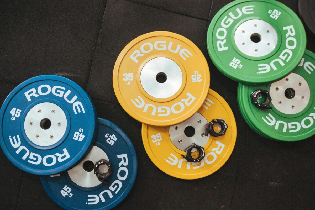 pexels photo 1092878 1092878 Colorful Rogue weight plates arranged on a gym floor visualizing fitness and strength.